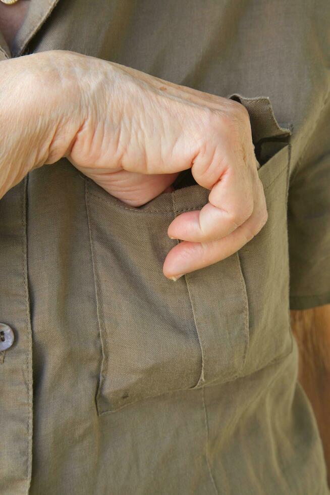 An old woman takes something from her pocket photo