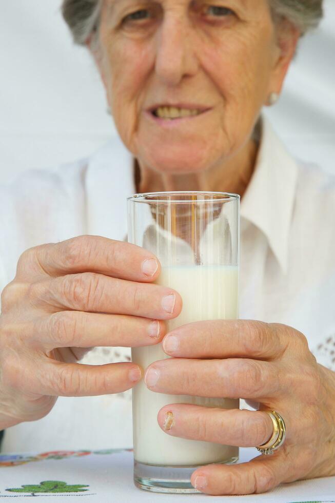 A glass of milk is kept by an old woman between 70 and 80 years old photo