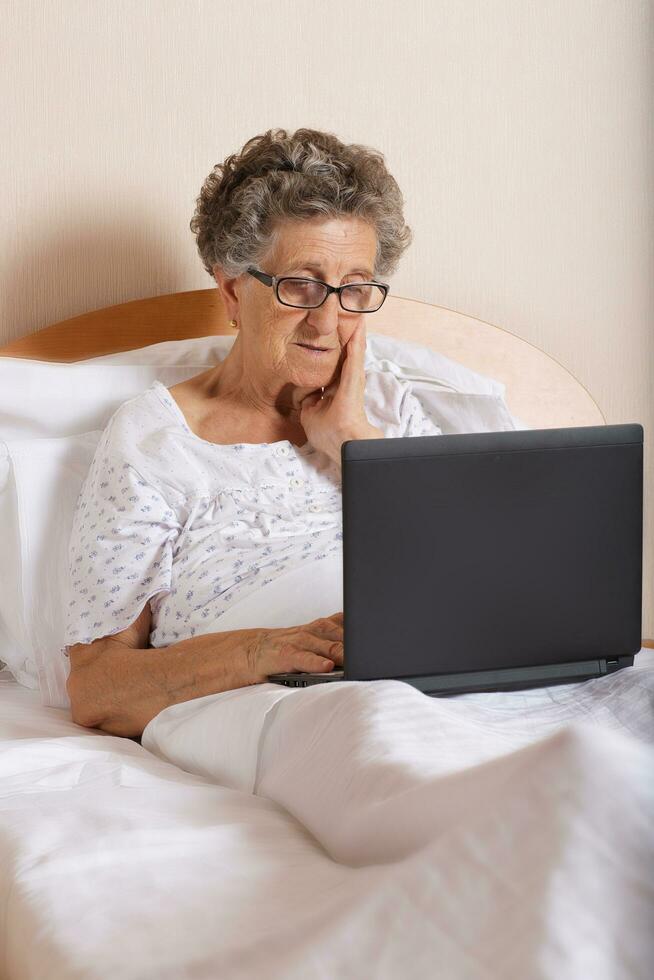Old woman is communicating through her computer wit hrelatives photo