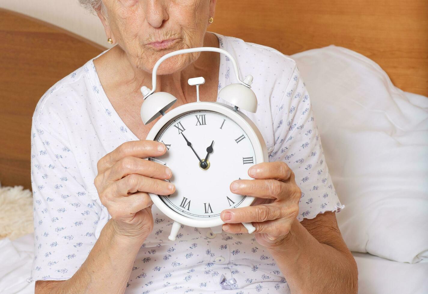 Old woman with vintage alarm clock photo