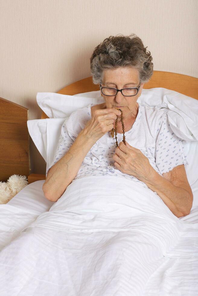 Old woman is praying in the bed photo