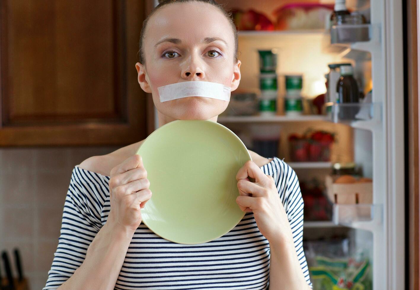 Young lady between is staying in front of the fridge. photo