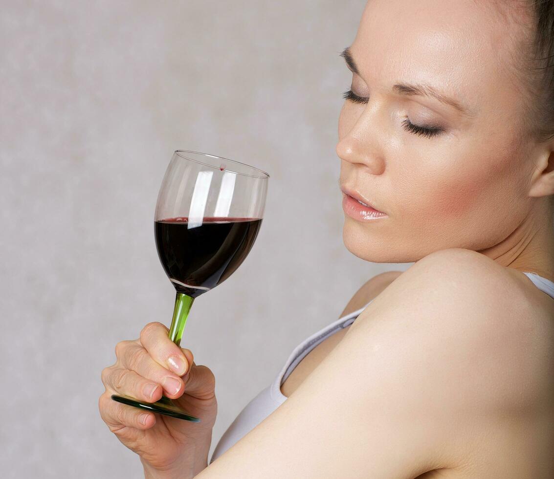 Young lady keeps a glass of red wine in her hand photo