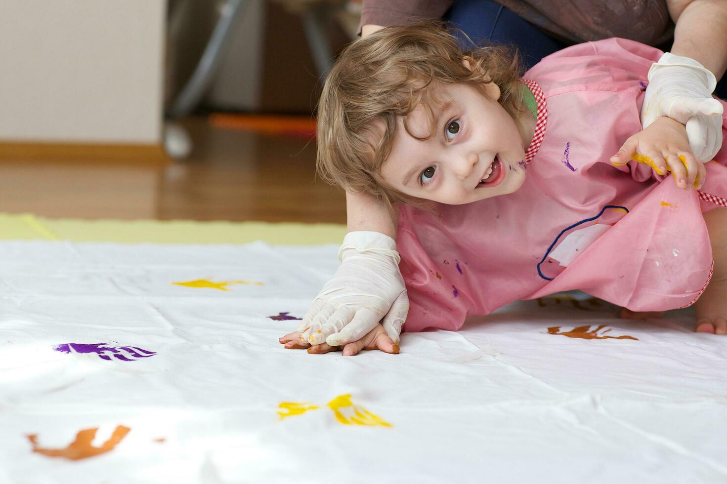 Child is painting white blanket with their palms photo