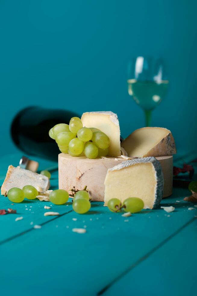 Cheese, grapes and wine on wooden cyan surface. photo