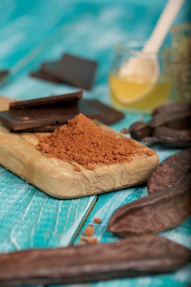 Carob pods and powder on a wooden surface. photo