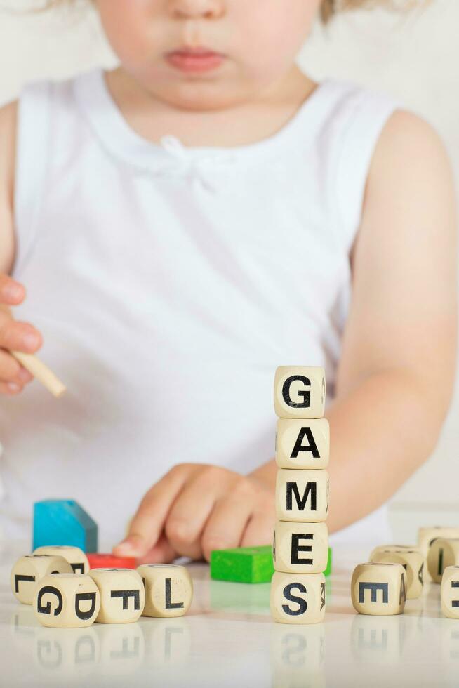 Small girl composes words from letters. Closeup photo