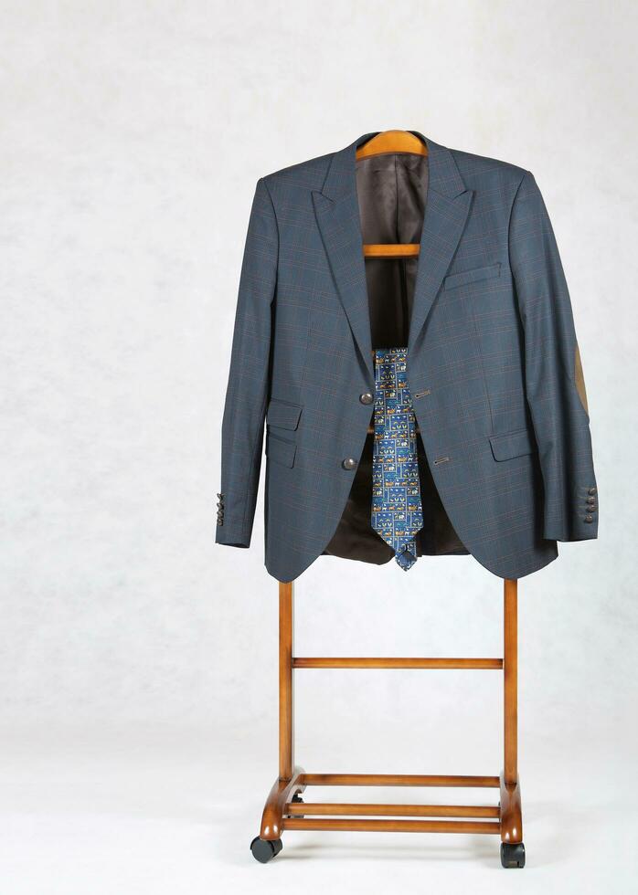 Male classical jacket and a tie are on a jacket hanger stand. photo