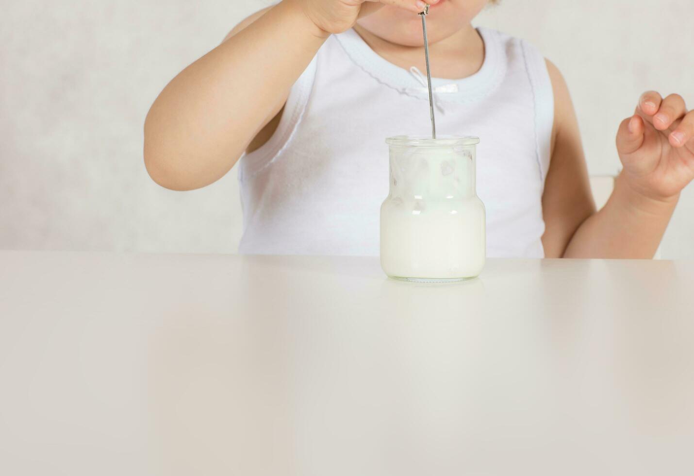 Small girl eats natural sugar free yogurt. Closeup photo