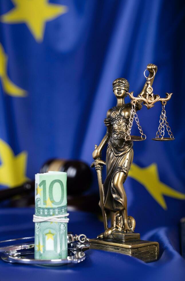 Pile of 100 euros surrounded by handcuffs on a flag of EU. photo