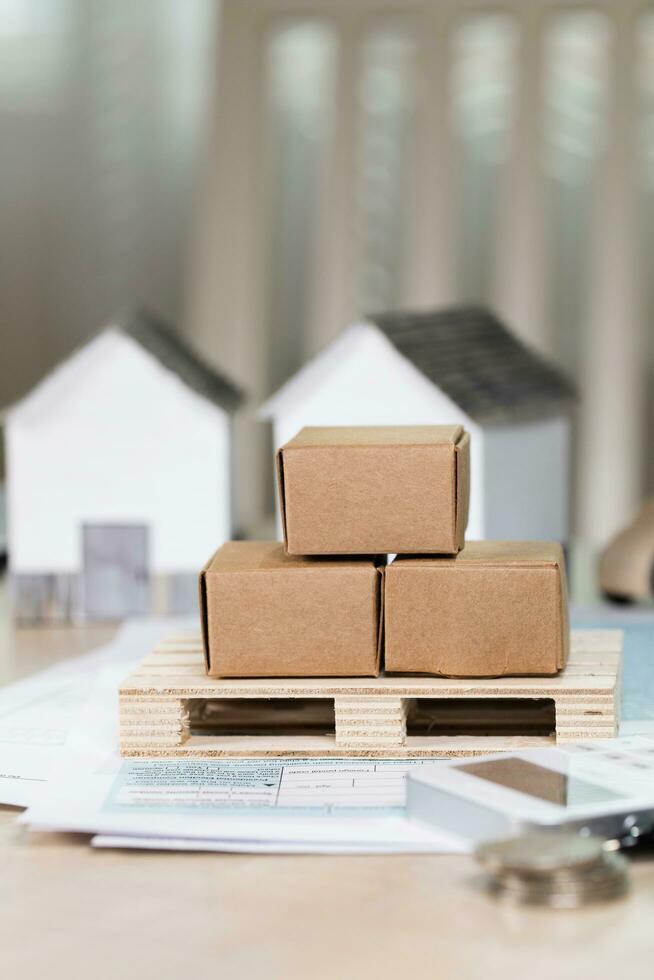 Pallet with carton boxes in front of small paper houses. photo