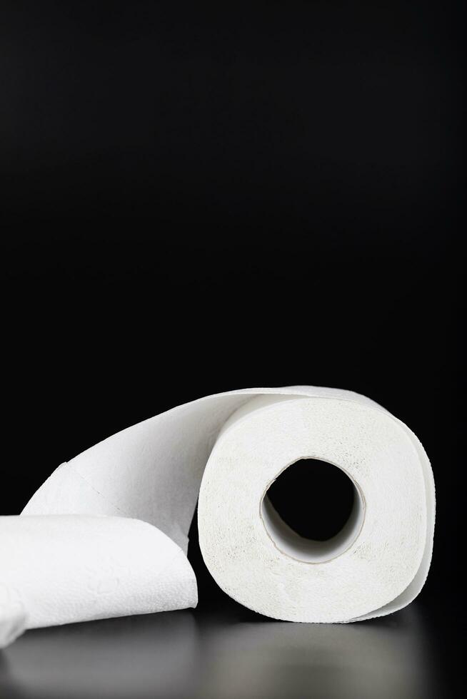 Roll of toilet paper on a black surface. photo