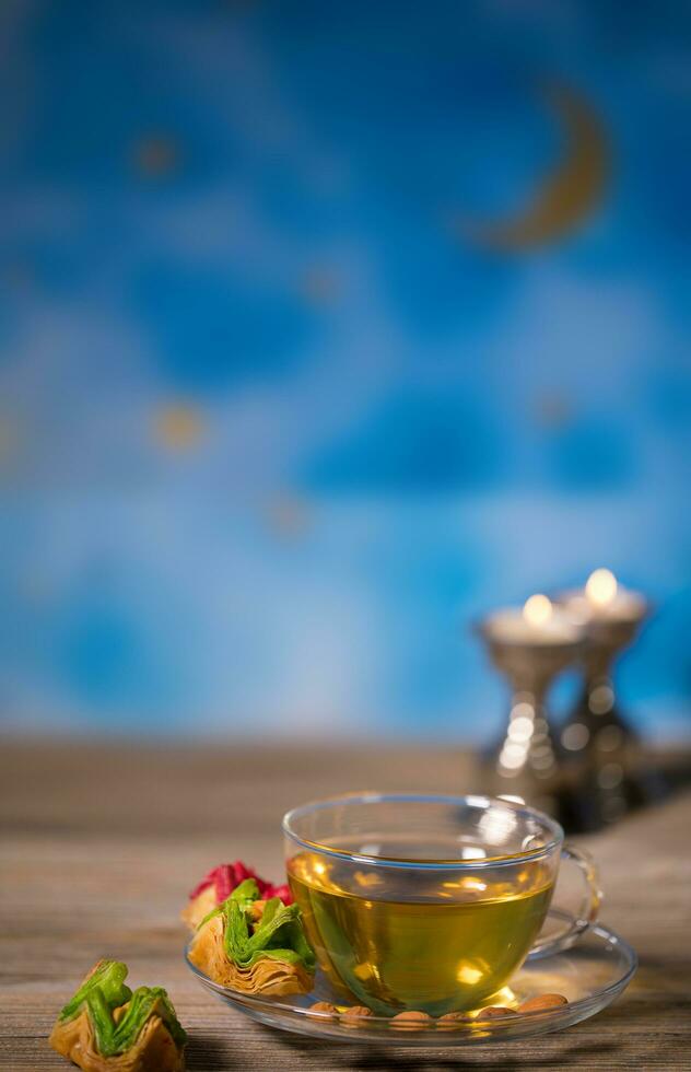 Tea in a glass cup with Arabic sweets on a wooden surface. photo