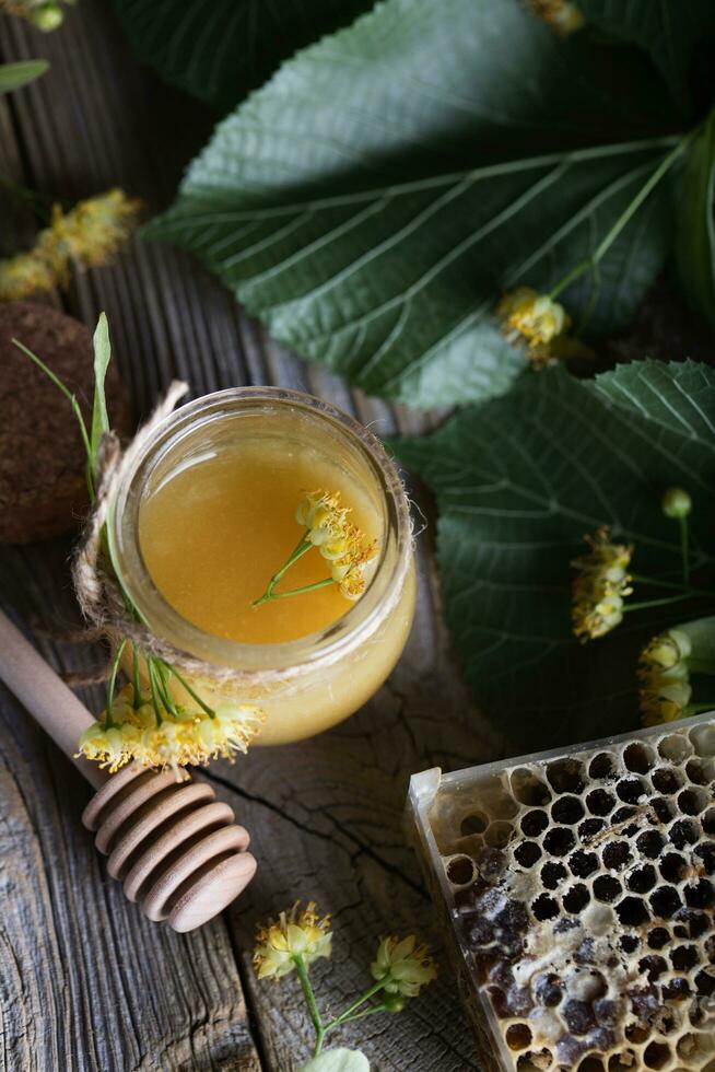 Linden blossoms honey in a glass bottle on a wooden surface. photo