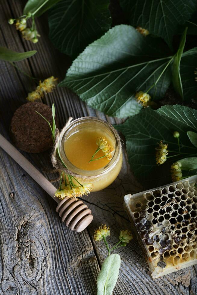 Linden blossoms honey in a glass bottle on a wooden surface. photo