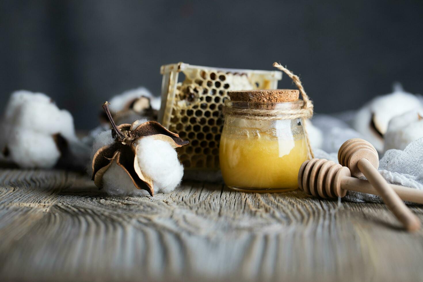 Cotton honey in a glass bottle on a wooden surface. photo