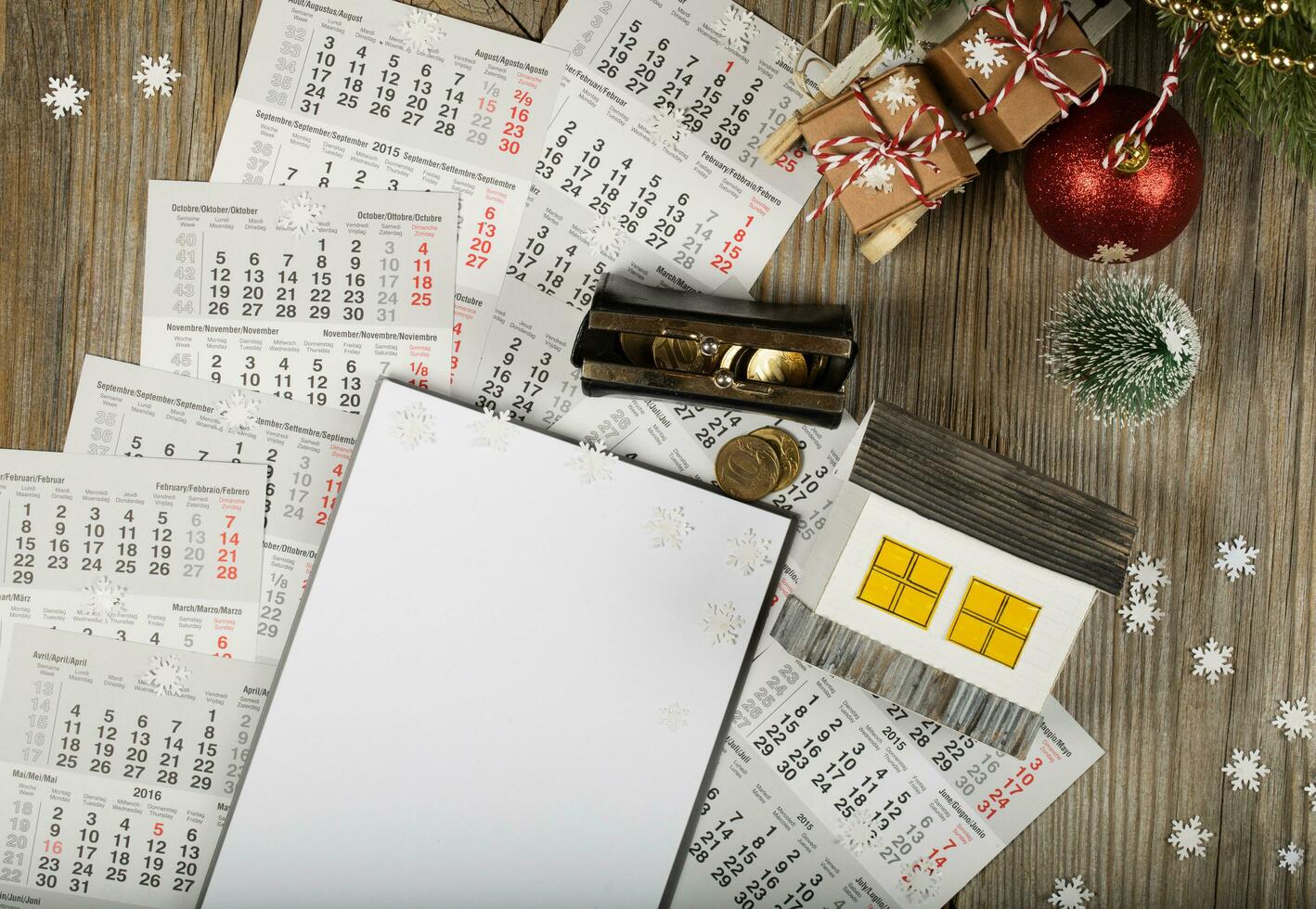 Blank sheet of paper and small paper house with coins on the New Year's background. photo