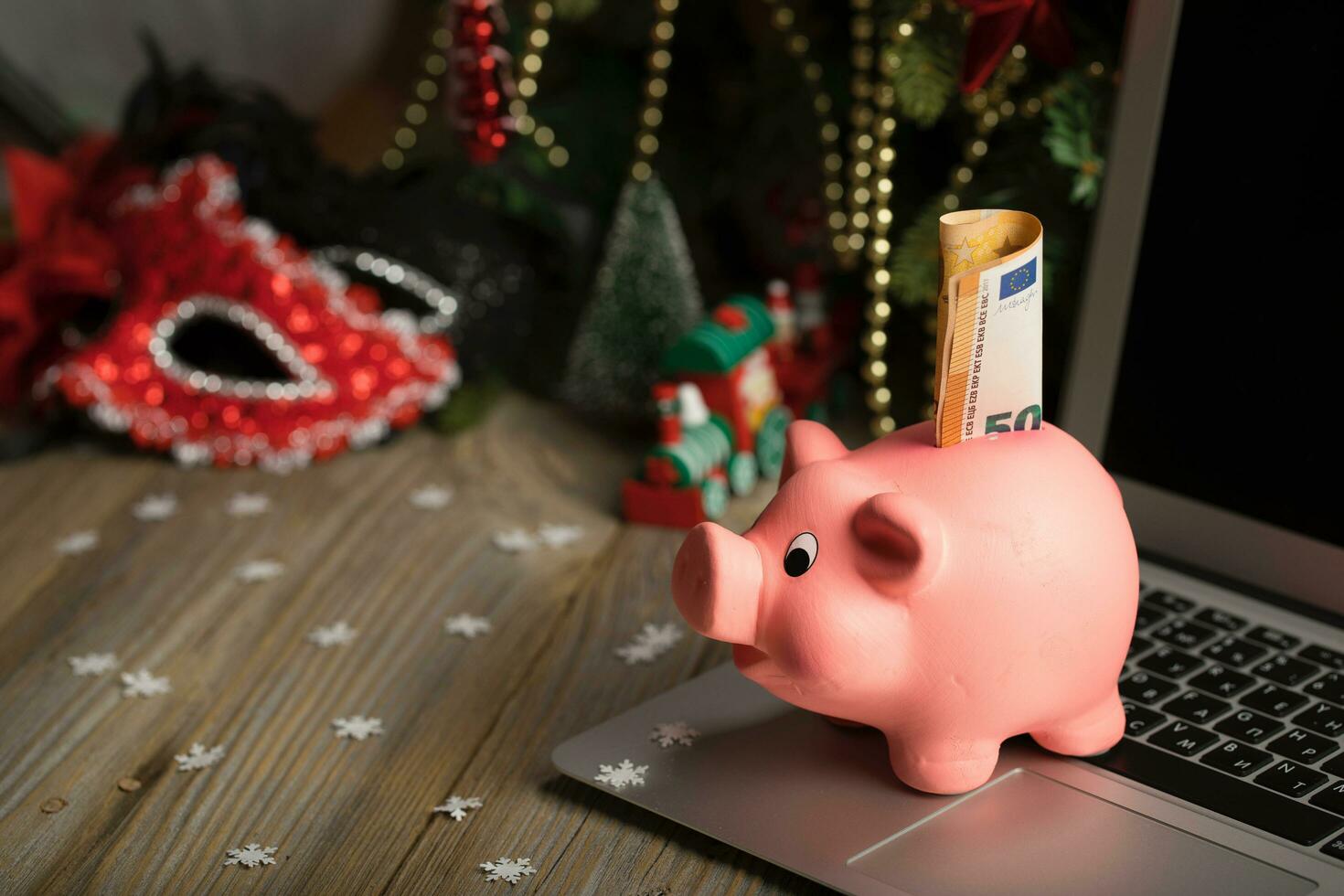 Pink piggy bank with banknote on a laptop. photo