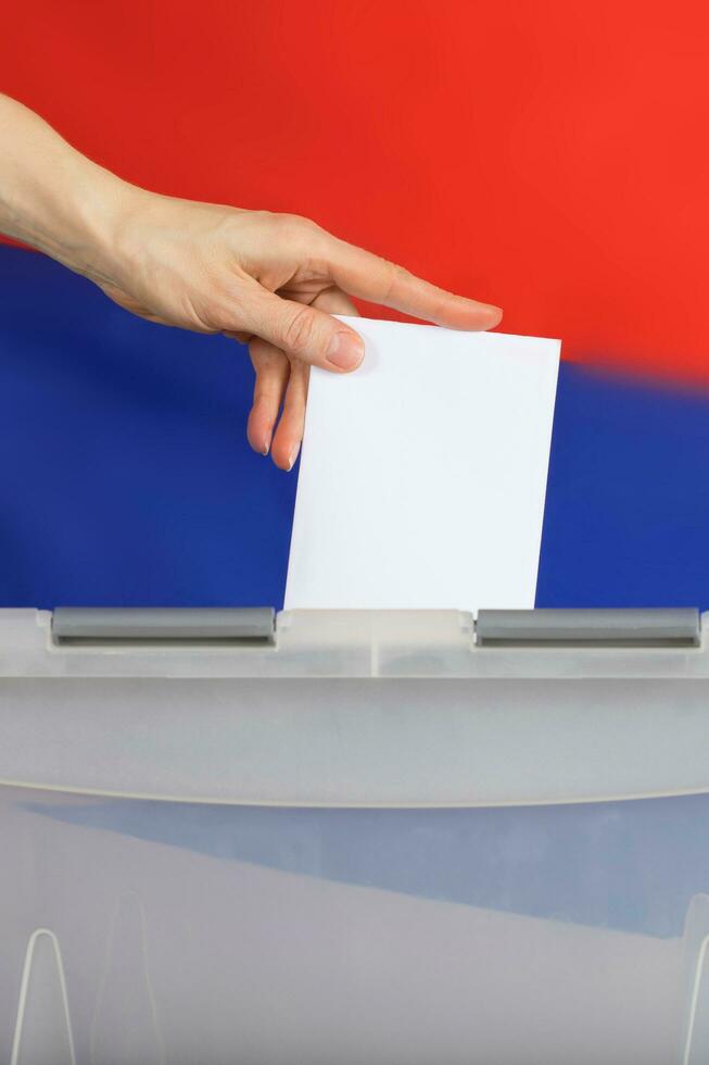 Female hand casts ballot paper in the ballot box. photo