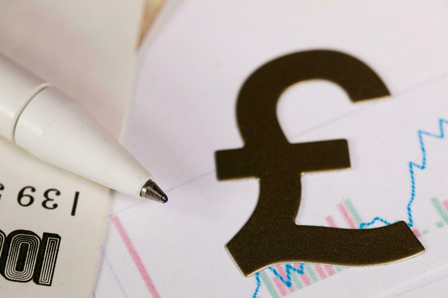 Pen on a banknote. Cutout of British pound sign in the background. photo