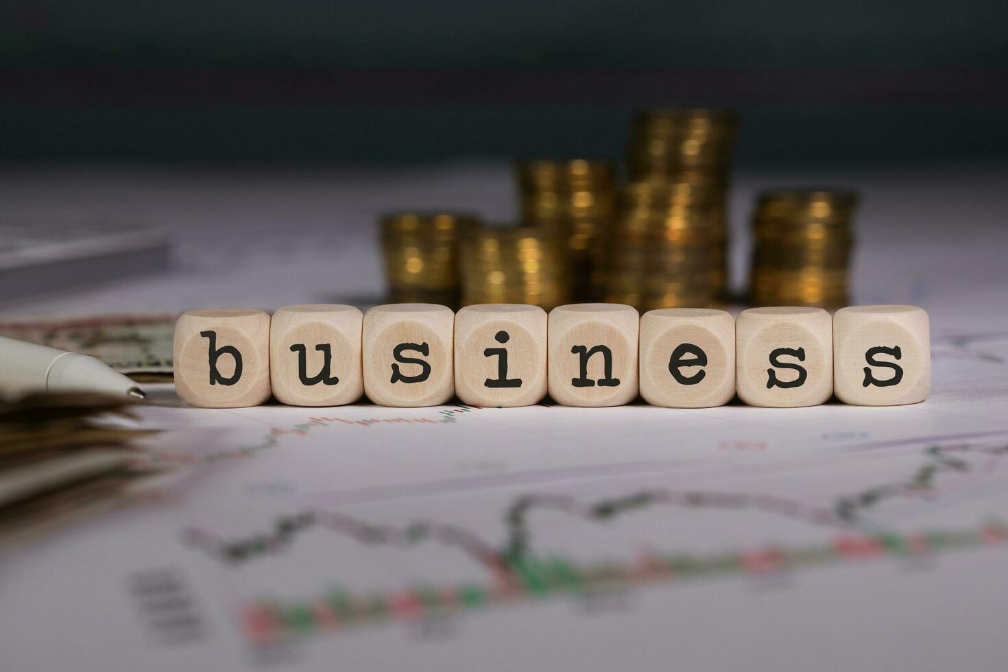 Word BUSINESS composed of wooden letter. Stacks of coins in the background. photo