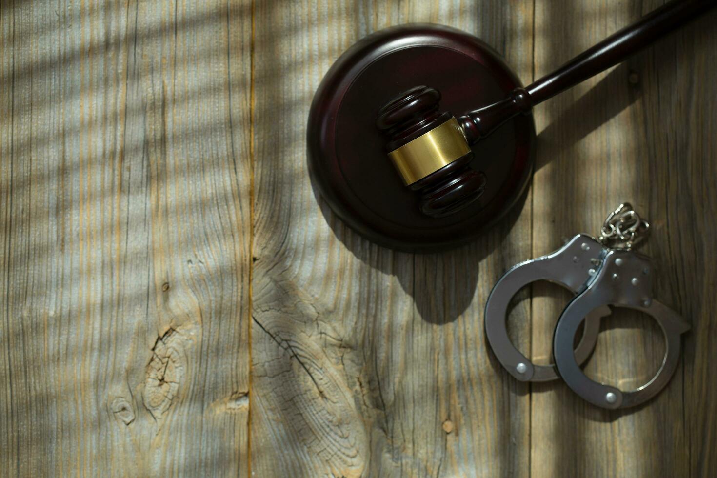 Wooden gavel on a wooden surface. Handcuff in the background photo