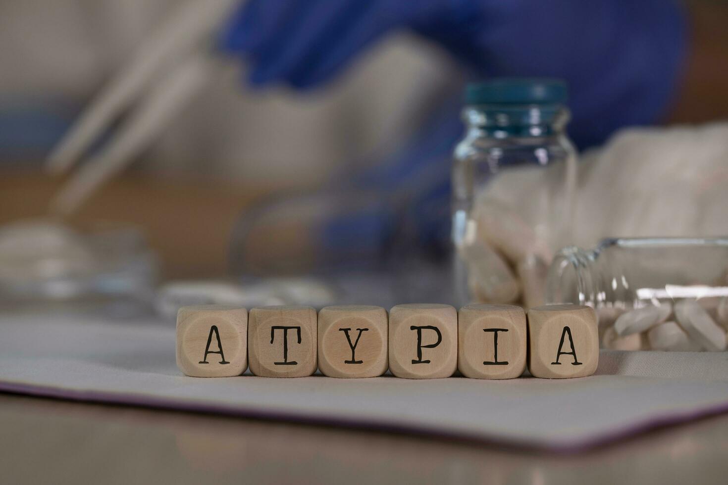 Word ATYPIA composed of wooden dices. Pills, documents and a pen in the background. photo