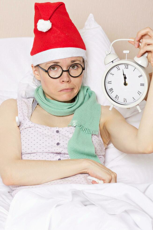 Sick young lady in her bed with alarm clock photo