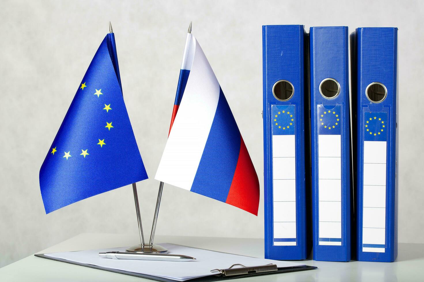 Two flags of the EU and Russia on a white table. Closeup photo