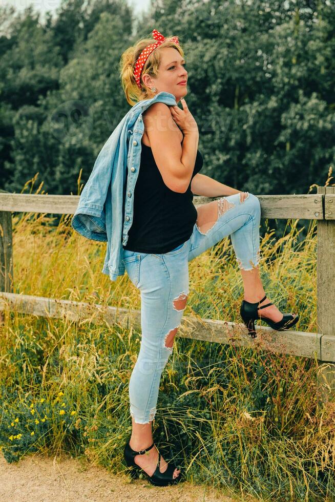 an attractive woman with hair bow and jeans outfit in nature photo