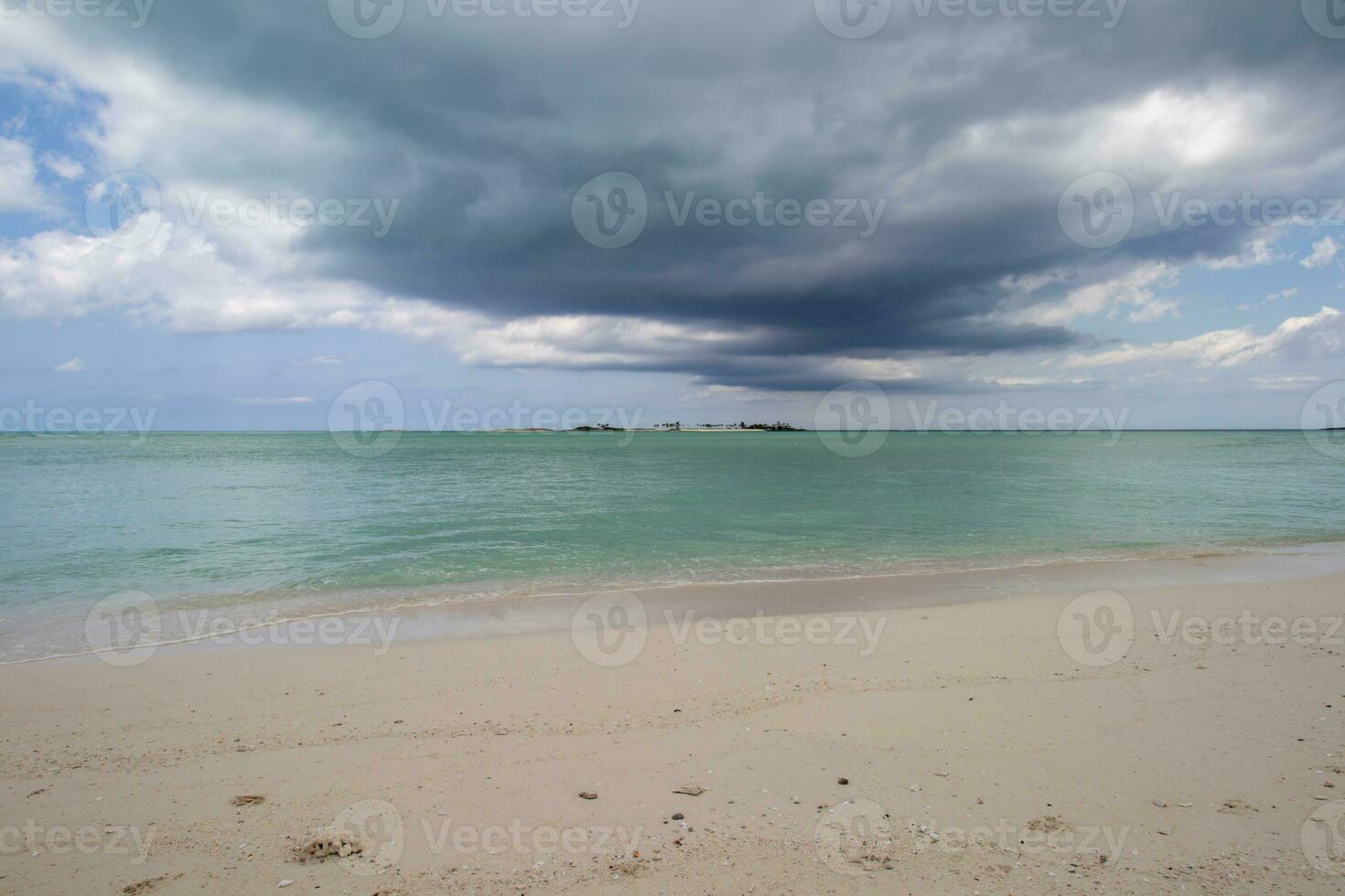 Tropical island off the coast of a sandy beach on a cloudy day photo