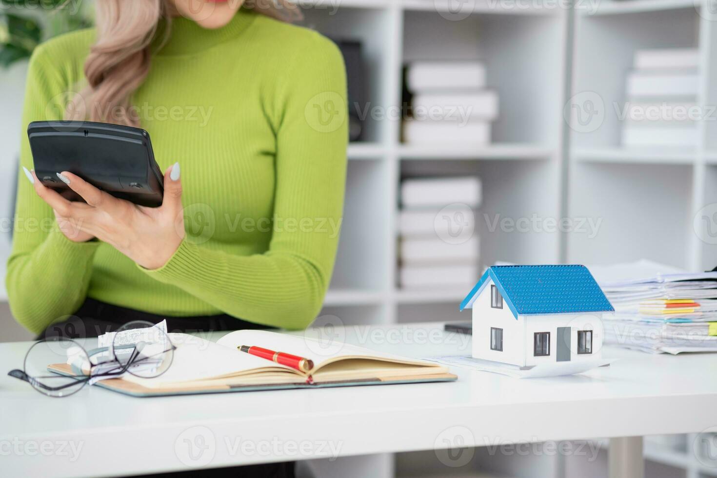 woman sitting on cozy sofa and planning and calculate expense and mortgage with calculator and home on desk, insurance and budget of residential, loan and residence, business and property concept. photo