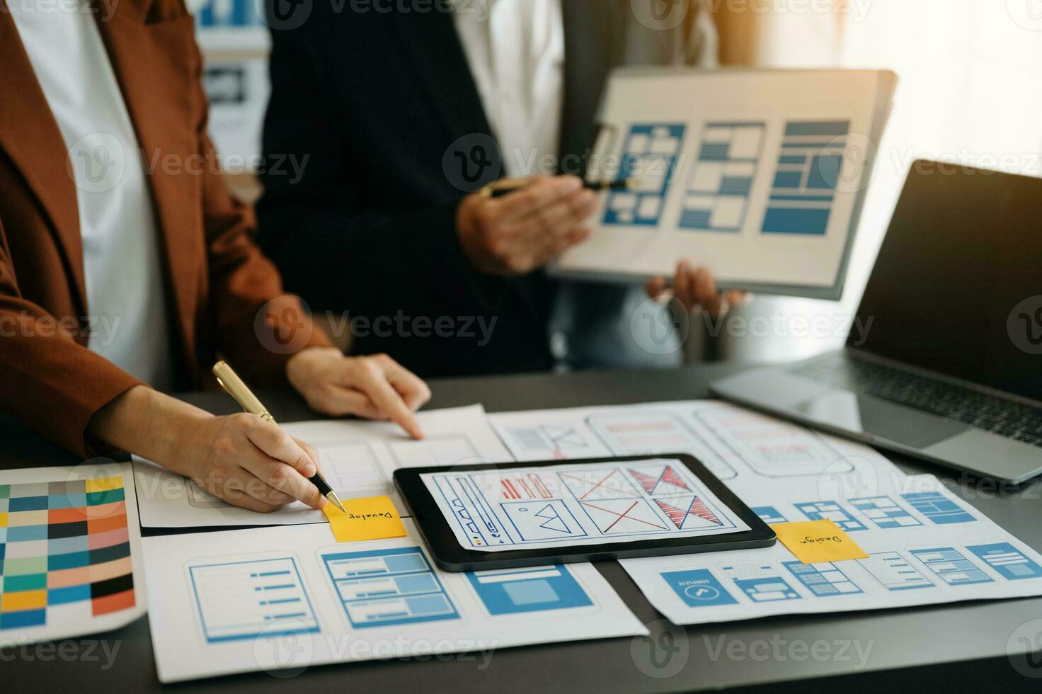 UX developer and ui designer brainstorming about mobile app interface wireframe design with customer breif and color code at office. photo