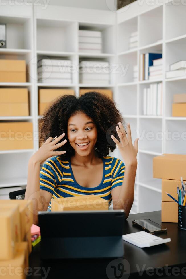 Small business entrepreneur SME freelance African woman working at home office, BOX,tablet and laptop online, marketing, packaging, delivery,  e-commerce concept photo
