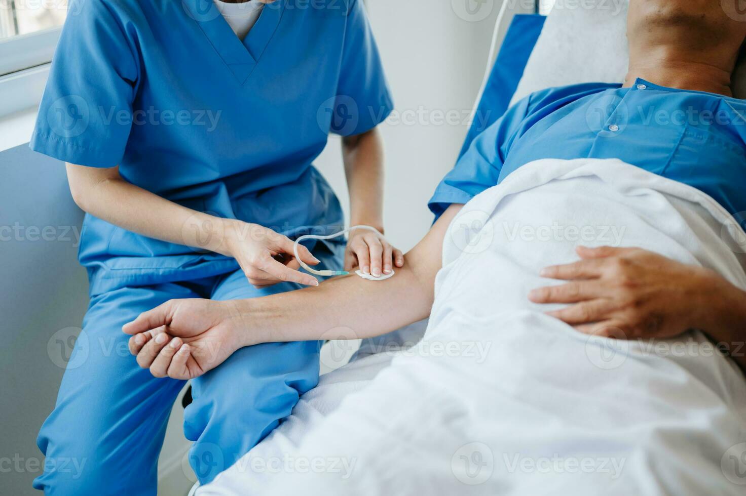 Friendly Female Head Nurse Making Rounds does Checkup on Patient Resting in Bed. She Checks tablet while Man Fully Recovering after Successful Surgery in hospital photo