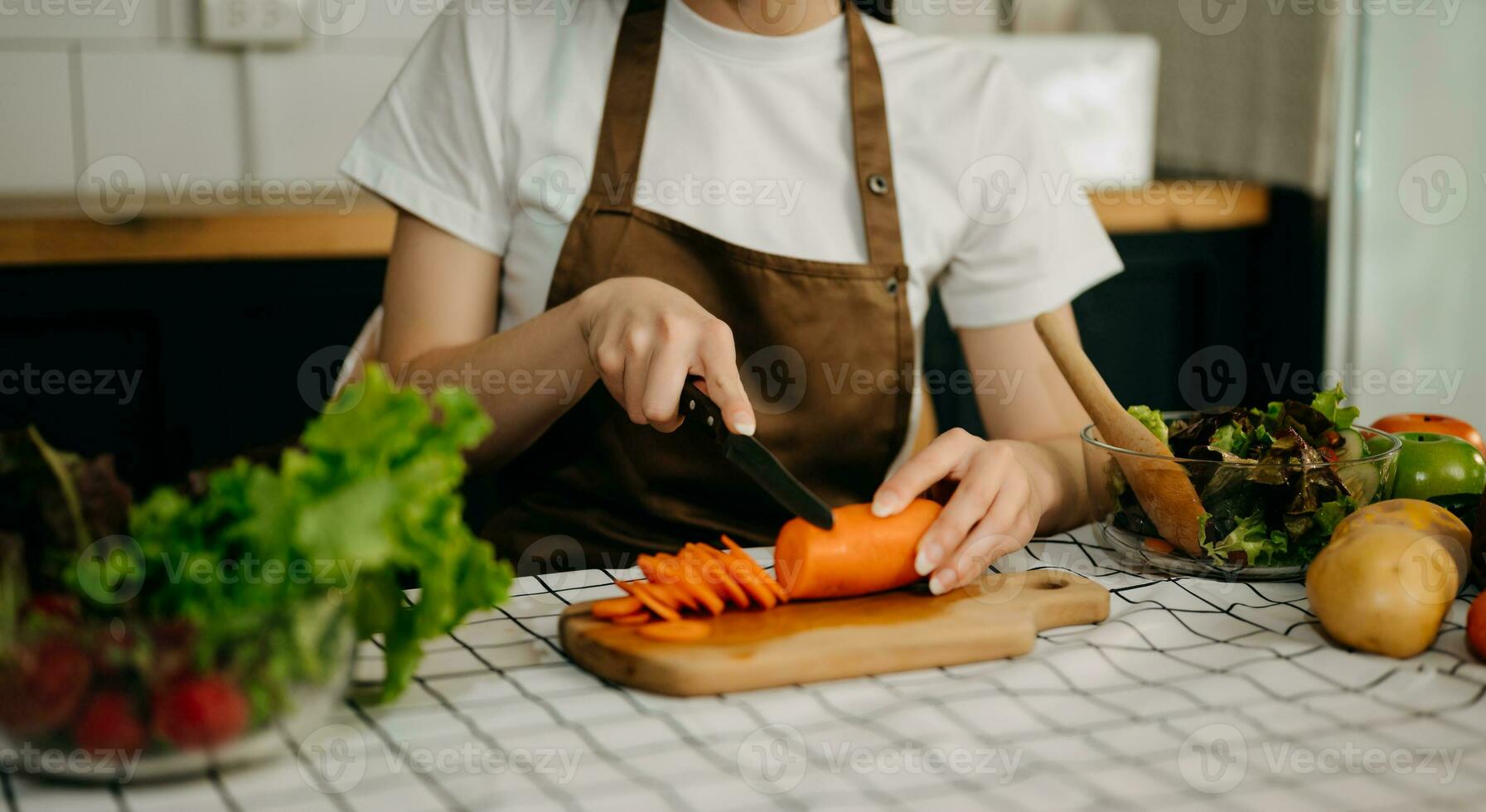 Close up young woman hands preparing a healthy salad. Cutting vegetables tomatoes on a cutting board on the home photo