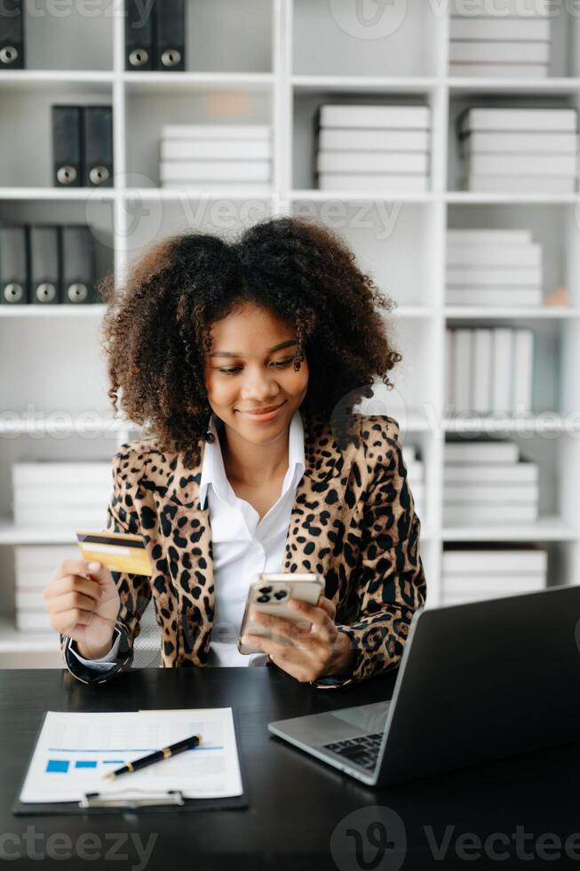 African Woman using smart phone for mobile payments online shopping,omni channel,sitting on table,virtual icons graphics interface screen photo
