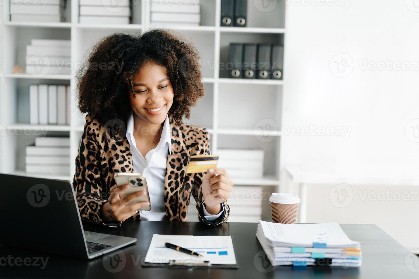 African Woman using smart phone for mobile payments online shopping,omni channel,sitting on table,virtual icons graphics interface screen photo