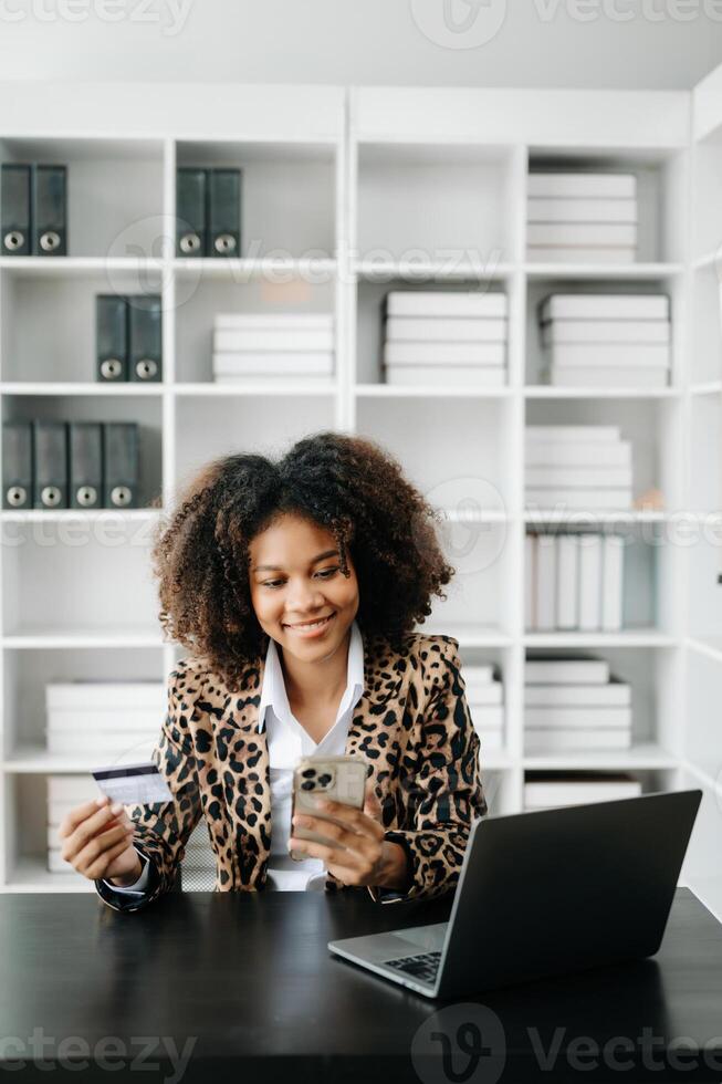 African Woman using smart phone for mobile payments online shopping,omni channel,sitting on table,virtual icons graphics interface screen photo