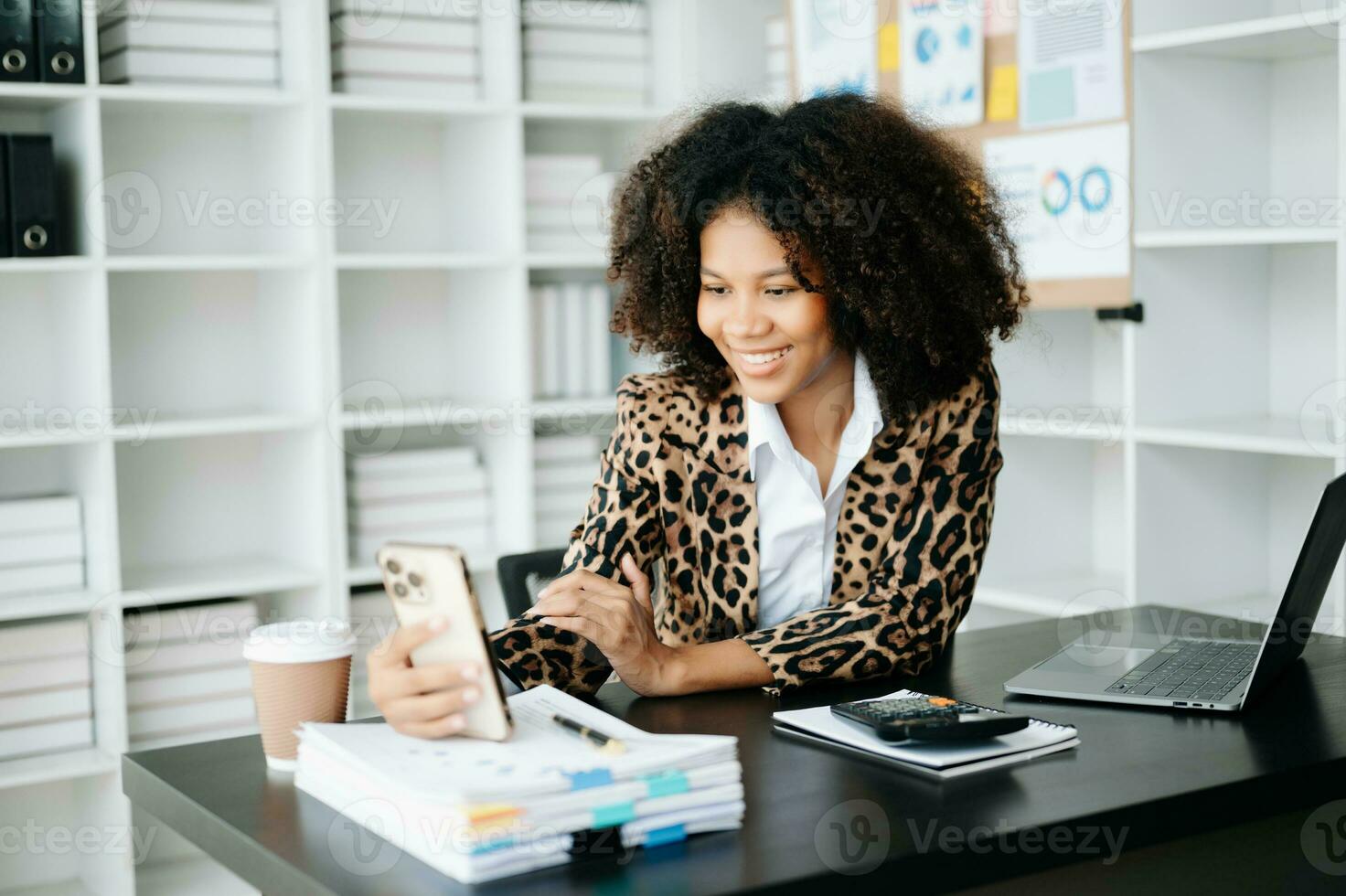 Young African woman typing on tablet and laptop while sitting at the working black table office photo