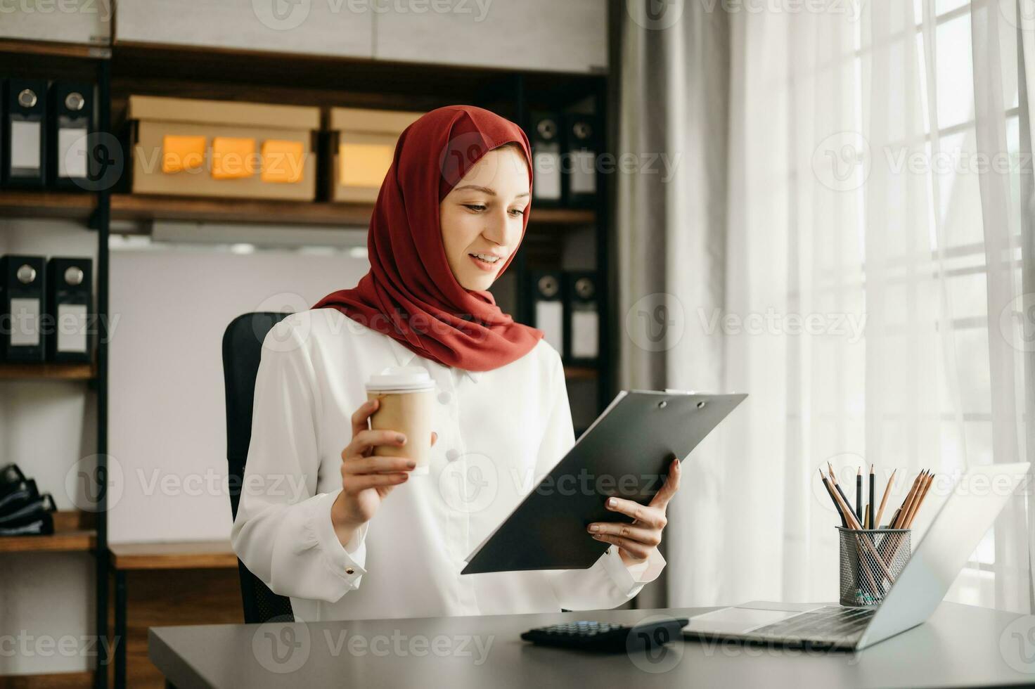 Young Arabic female entrepreneur wearing a hijab working online with a laptop at office photo