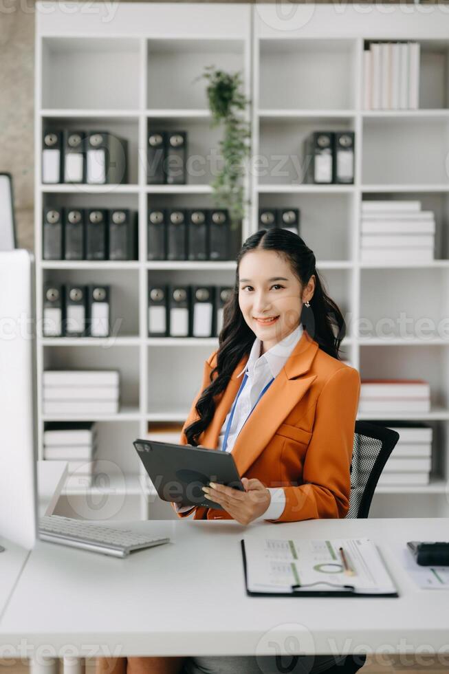 Business woman using tablet and laptop for doing math finance on an office desk, tax, report, accounting, statistics, and analytical research concept in office photo
