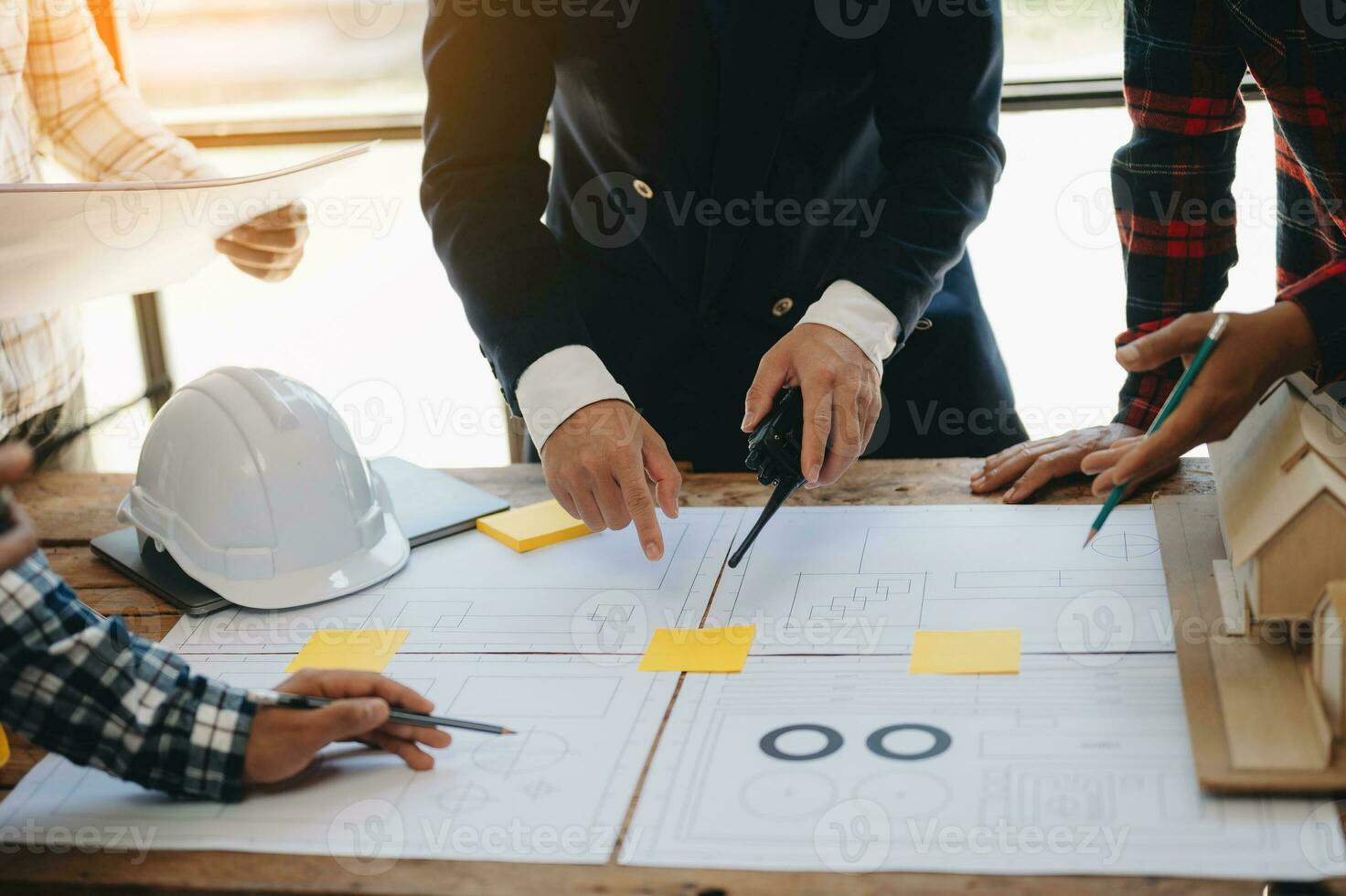 Engineer desk with object paper and tablet with blurry engineer teamwork hardworking to consults about their building project.in office photo