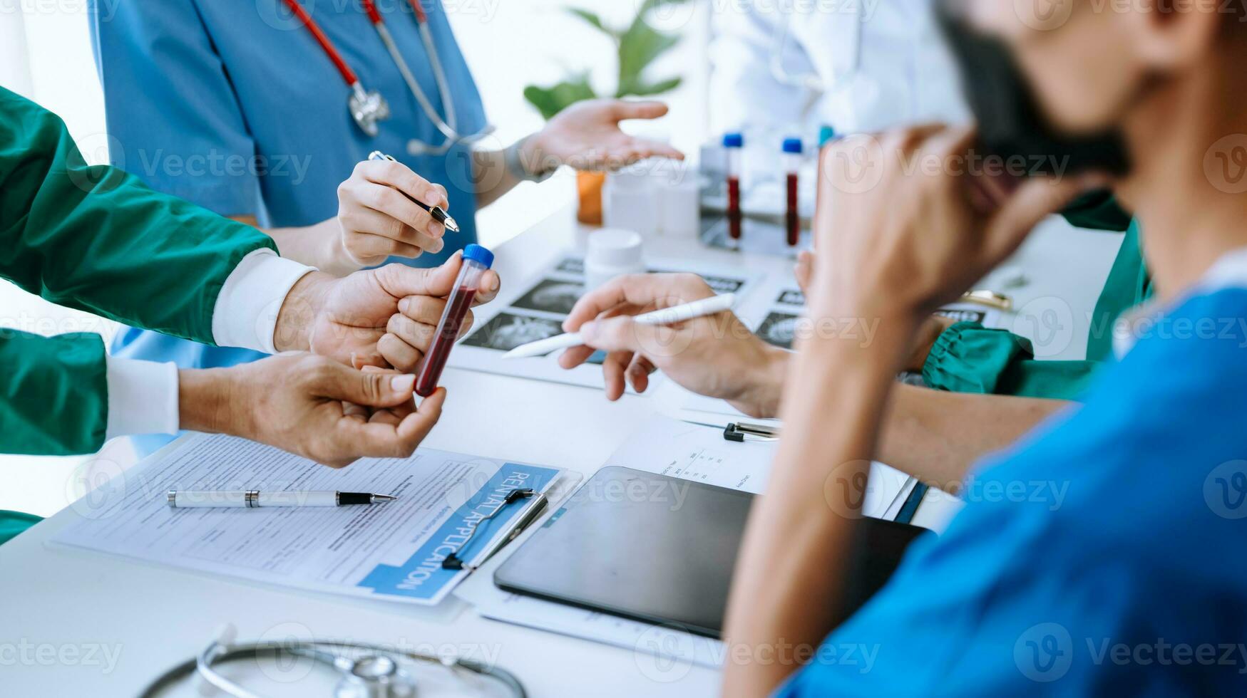 Medical team having a meeting with doctors in white lab coats and surgical scrubs seated at a table discussing a patients working online using computers photo