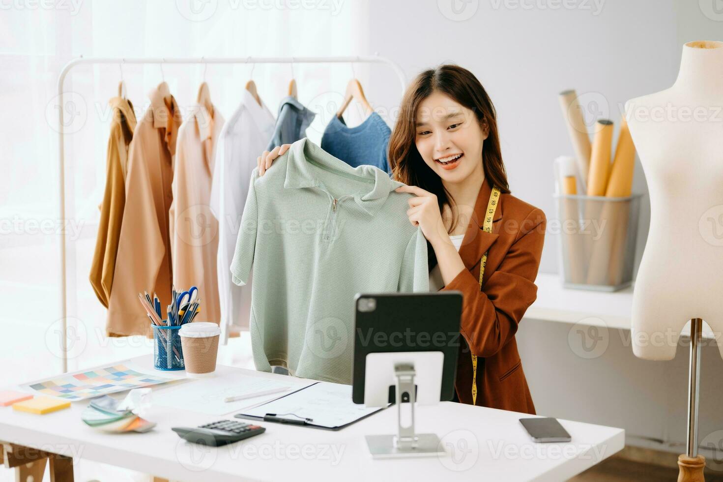 Fashion blogger concept, Young Asian women selling clothes on video streaming.Startup small business SME, using smartphone or tablet taking receive and checking photo