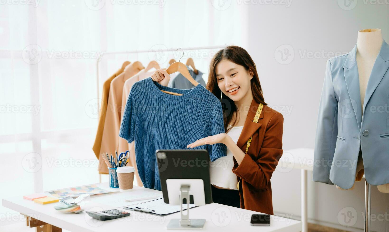 Fashion blogger concept, Young Asian women selling clothes on video streaming.Startup small business SME, using smartphone or tablet taking receive and checking photo