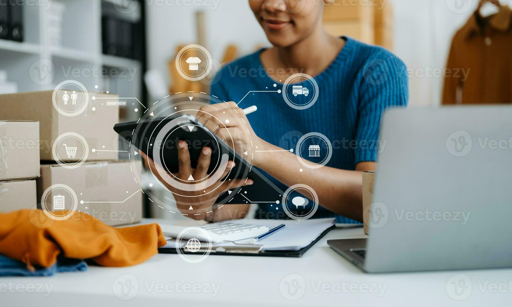African  Woman hand using a laptop, smartphone and tablet and writing notebook at the office of her business online shopping. In home with virtual icon photo
