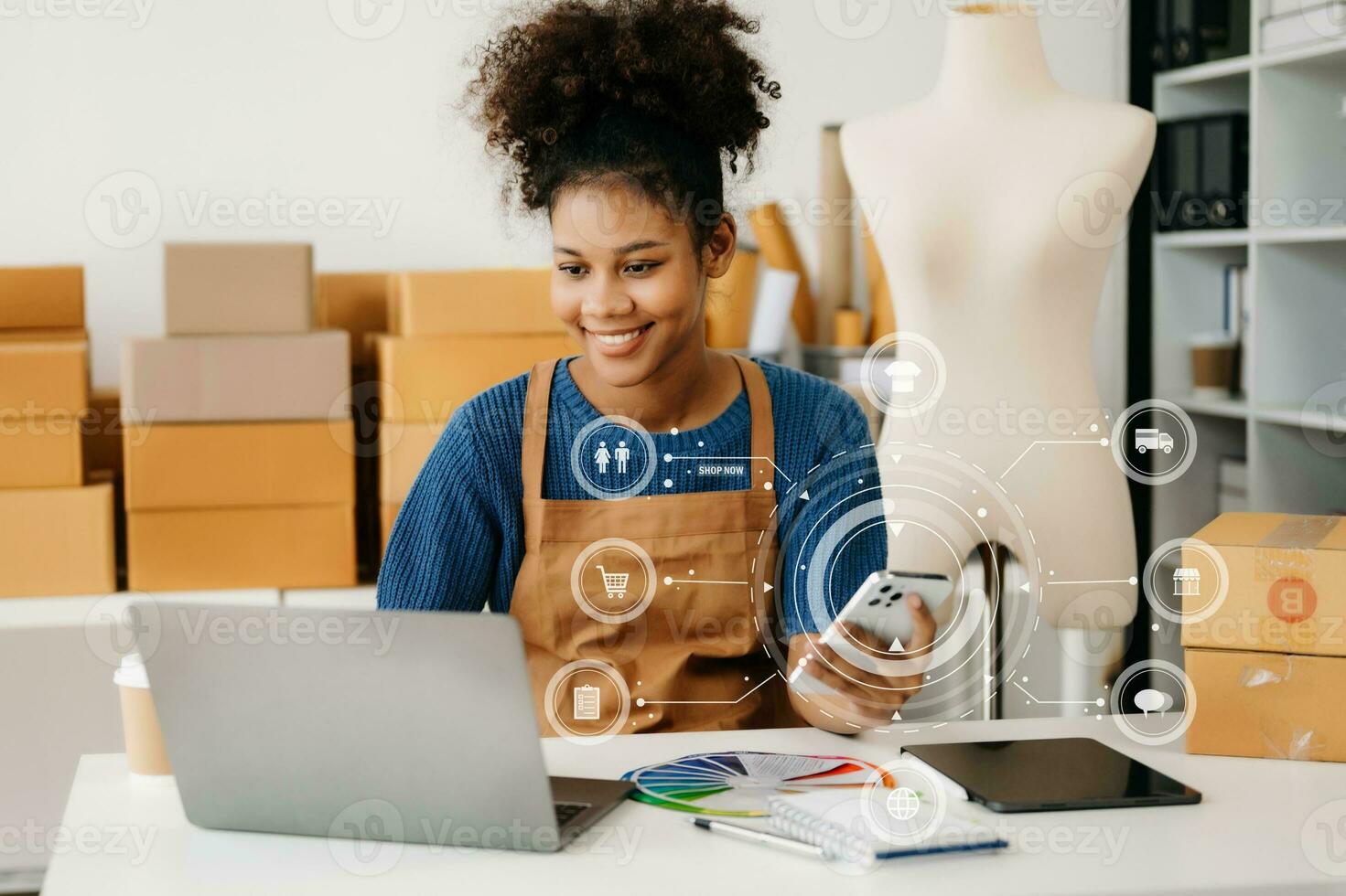 African Woman using a laptop, smartphone and tablet and writing notebook at the modern office of her business online shopping. In home with virtual icon photo