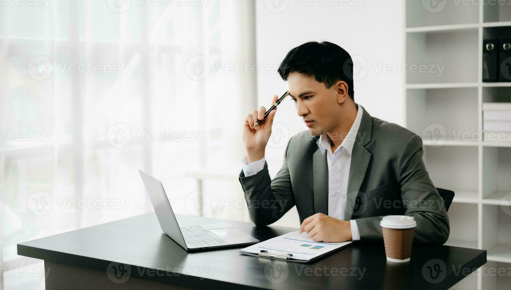 Young business man working at office with laptop, tablet and taking notes on the paper. photo