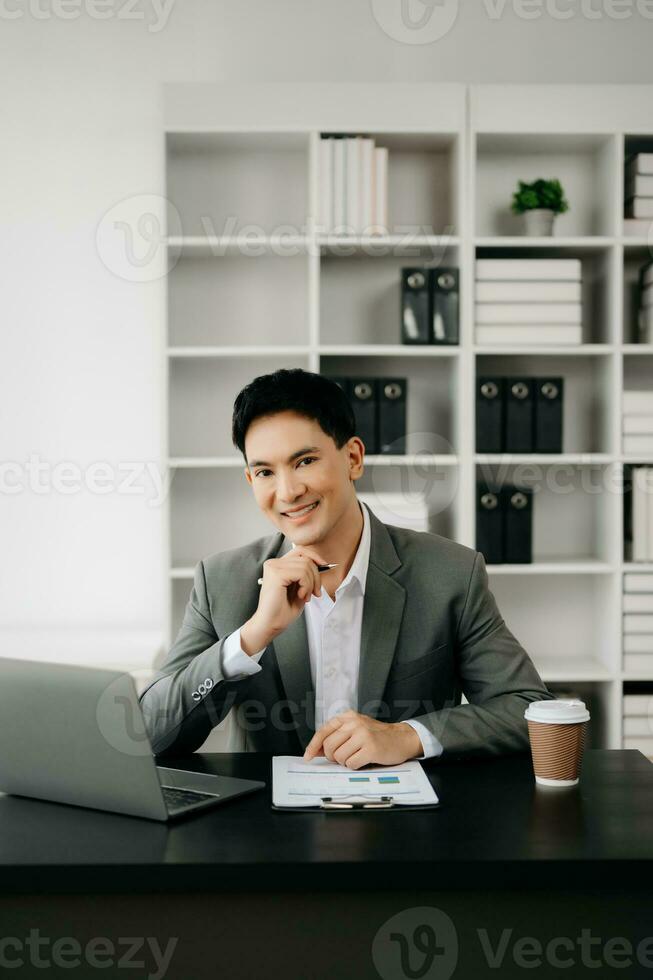 Young business man working at office with laptop, tablet and taking notes on the paper. photo